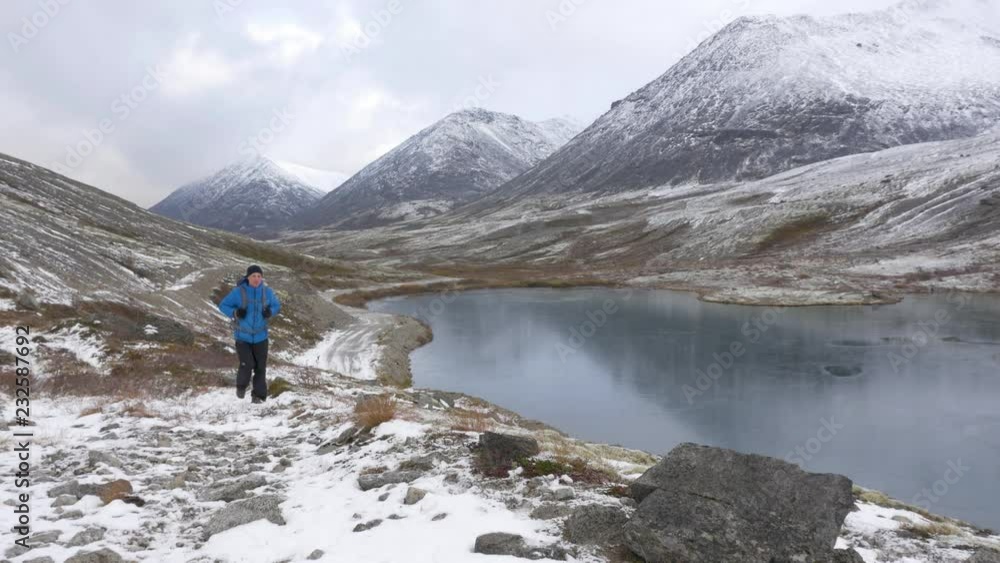 A middle-aged man traveling with a backpack in the mountains. He enjoys freedom and active life. A middle-aged man traveling with a backpack in the mountains. He enjoys freedom and active life.