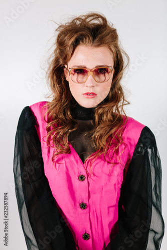 1980's studio portrait of a redheaded woman with curly hair in era specific cerise top with shoulderpads and sheer sleeves photo