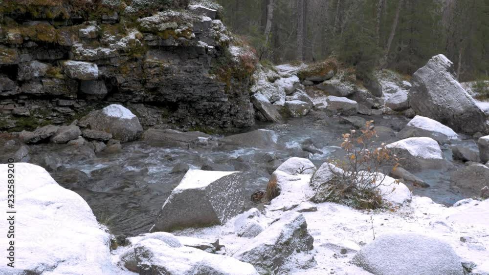 The stream flows in the mountains along the snowy shores. On a cloudy autumn day. The stream flows in the mountains along the snowy shores. On a cloudy autumn day.