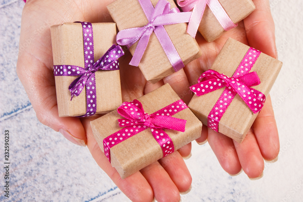 Hands of woman with gifts for Christmas or other celebration on snow background