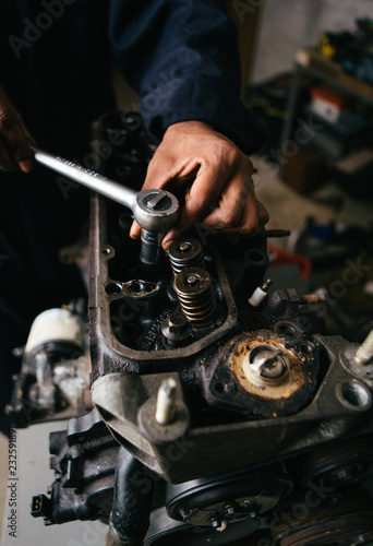 Mechanic fixing an engine for a head gasket repair in a garage.