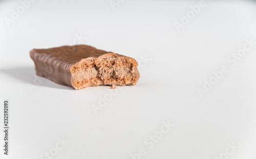 Chocolate biscuit with a bite taken on a white