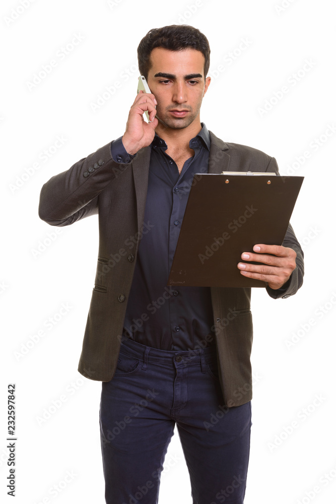 Persian businessman using phone and holding clipboard Persian businessman using phone and holding clipboard