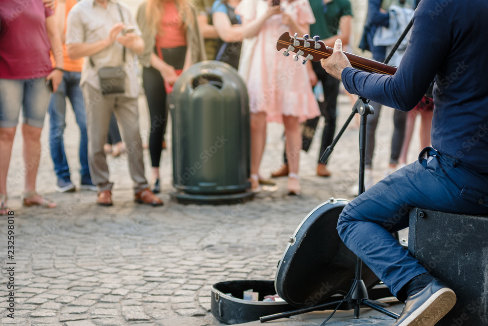 Obraz premium Uliczny muzyk bawić się gitarę na miasto ulicie w lecie