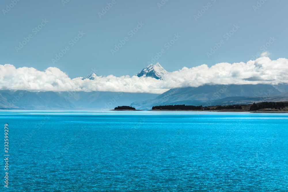 Blue water of lake Pukaki, Mount Cook, and cloudy sky, New Zealand