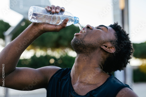 African american man drinking water after to play basketball.