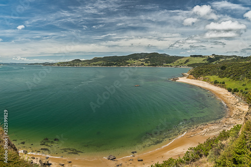 Panoramic view of the beach, white sand, blue water of the ocean and mountains and cloudy blue sky