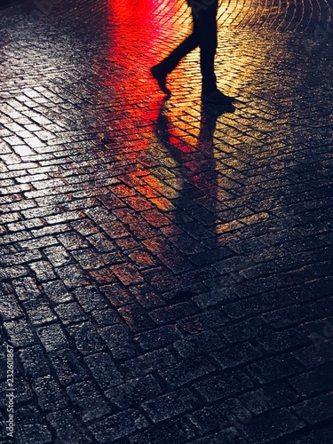 Unrecognizable person walking on asphalt by night photo