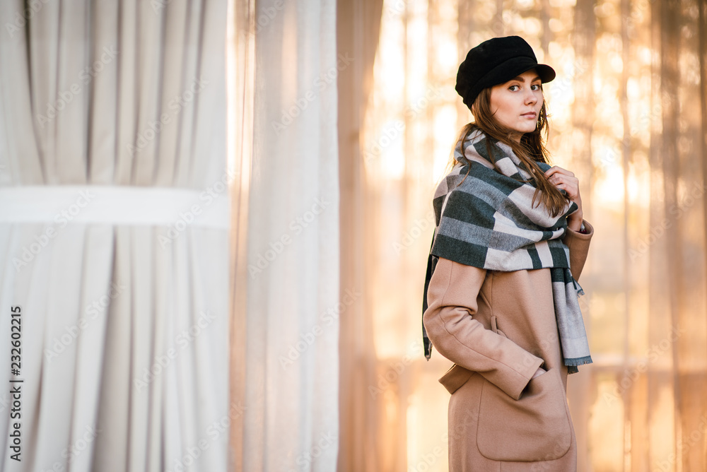 young beautiful girl in coat and hat outdoors, woman walks in park