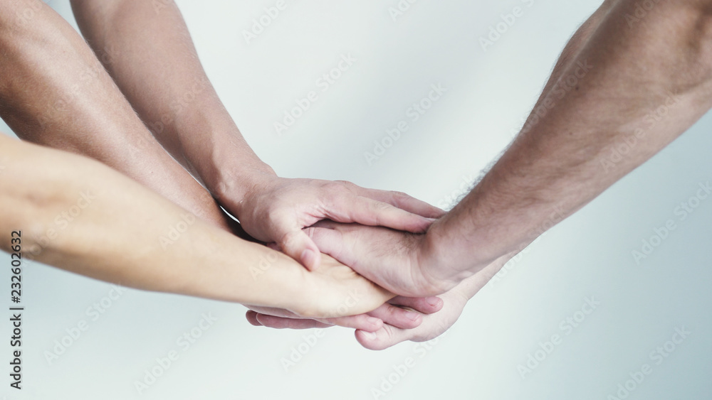 Fototapeta premium Four hands getting together on a white background.