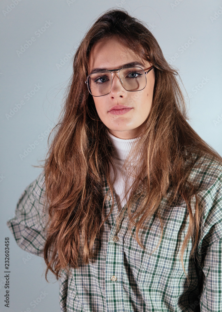 1980's womans studio portrait with era specific steel rimmed eyeglasses, turtleneck and checked shirt. 1980's womans studio portrait with era specific steel rimmed eyeglasses, turtleneck and checked shirt.