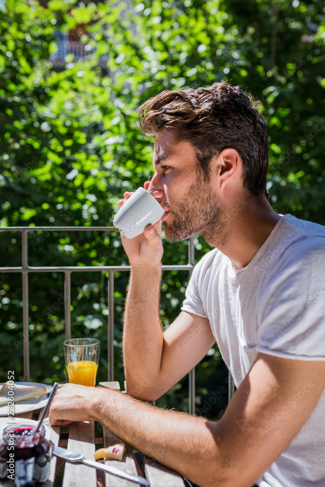 Young man relaxing on balcony having coffee Young man relaxing on balcony having coffee