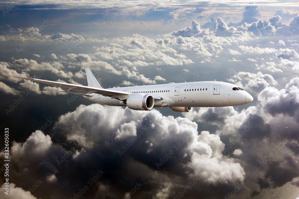 White passenger plane in flight. The plane flies against a background of clouds and mountain landscape. Aircraft side view. White passenger plane in flight. The plane flies against a background of clouds and mountain landscape. Aircraft side view.