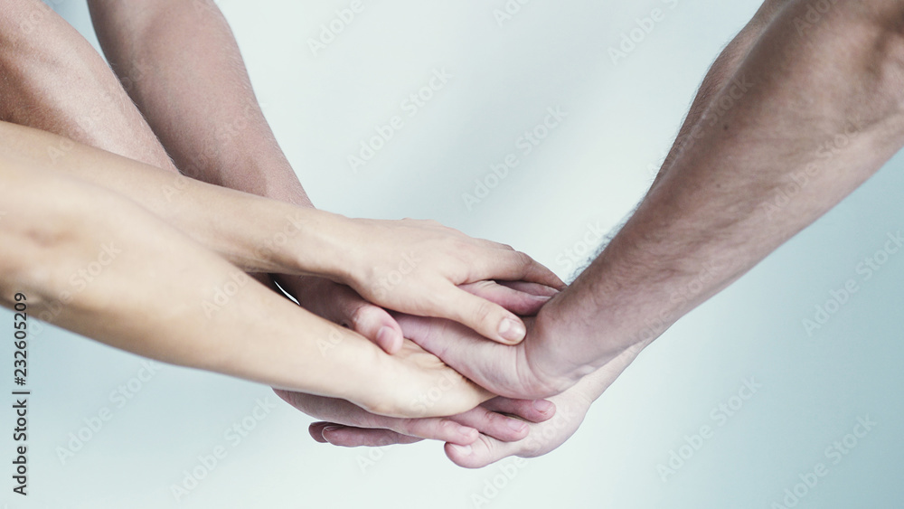 Fototapeta premium Four hands getting together on a white background.
