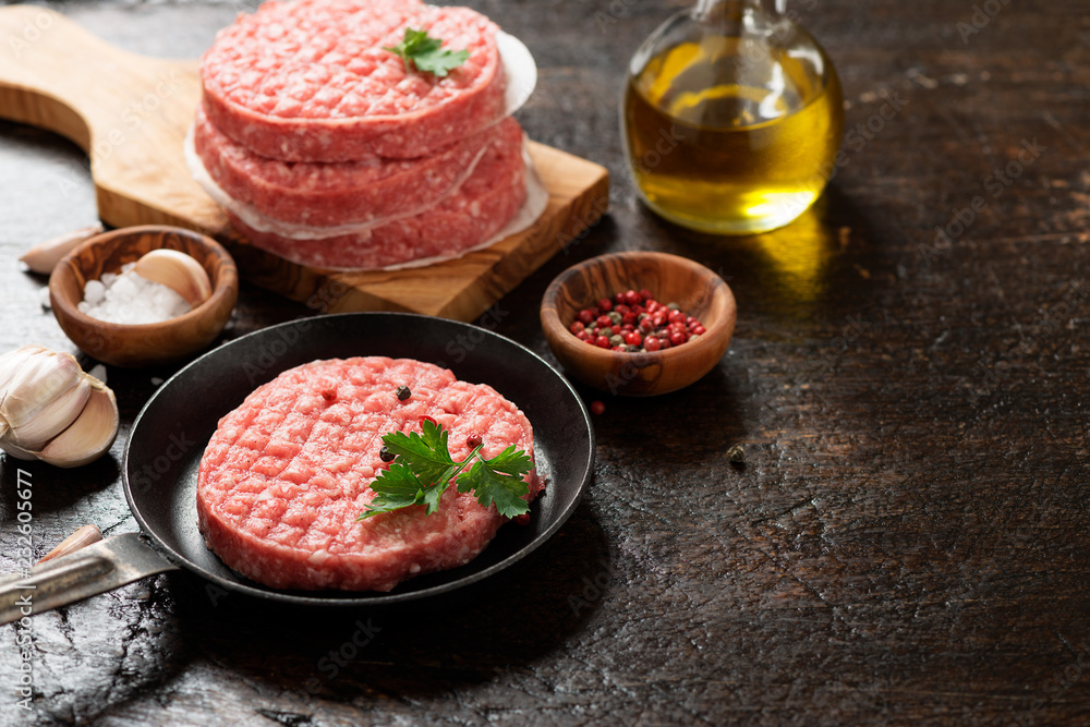 Raw Ground beef meat Burger steak cutlets on dark wooden background. Raw Ground beef meat Burger steak cutlets on dark wooden background.