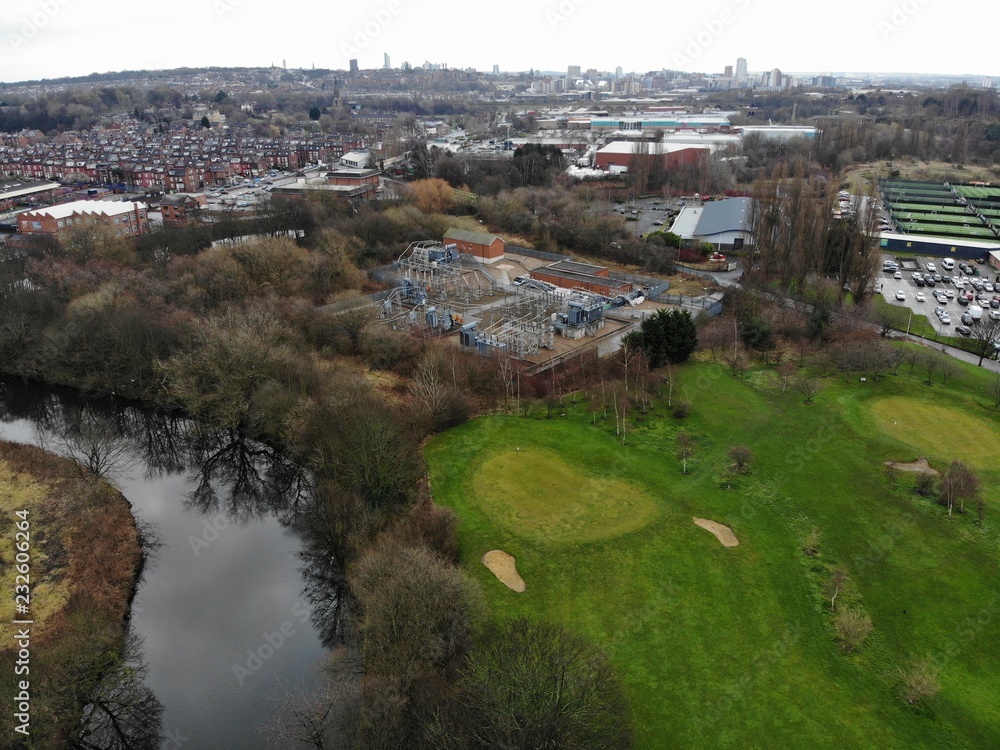 Aerial shot of a Golf course showing houses and trees with green grass.