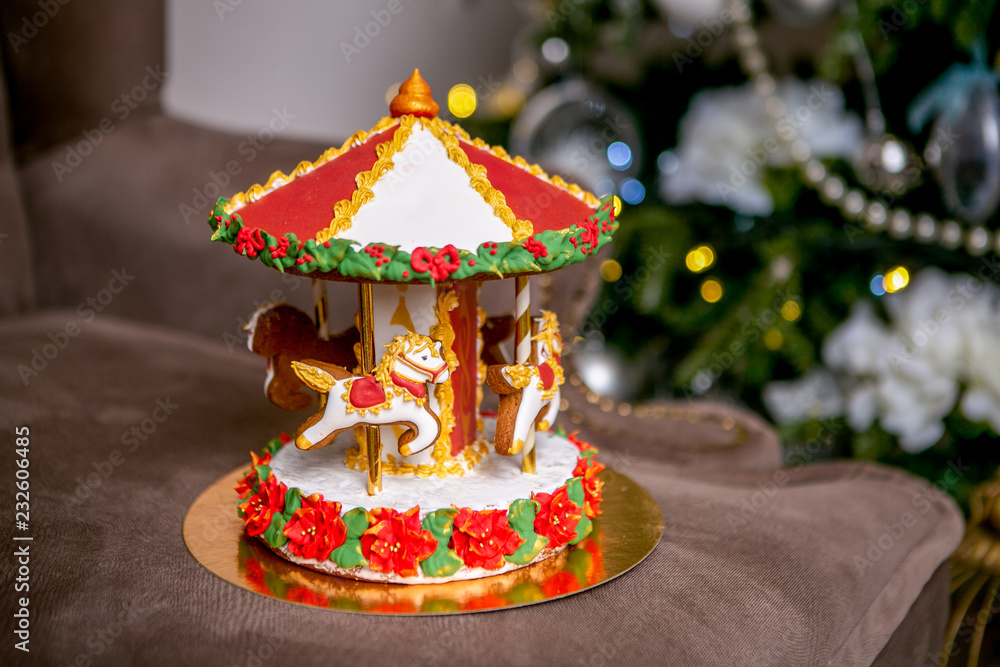 Gingerbread carousel in front of defocused lights of Chrismtas decorated fir tree. Holiday sweets. New Year and Christmas theme. Festive mood