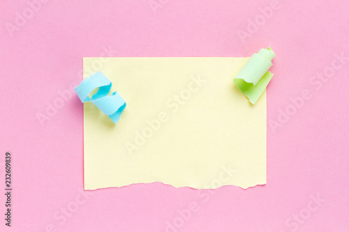 Celebration concept. Colorful party streamers and piece of torn colored note paper on a pink background. Copy space