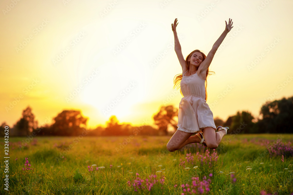 Happy cheerful girl is jumping on nature over the summer sunset background Happy cheerful girl is jumping on nature over the summer sunset background