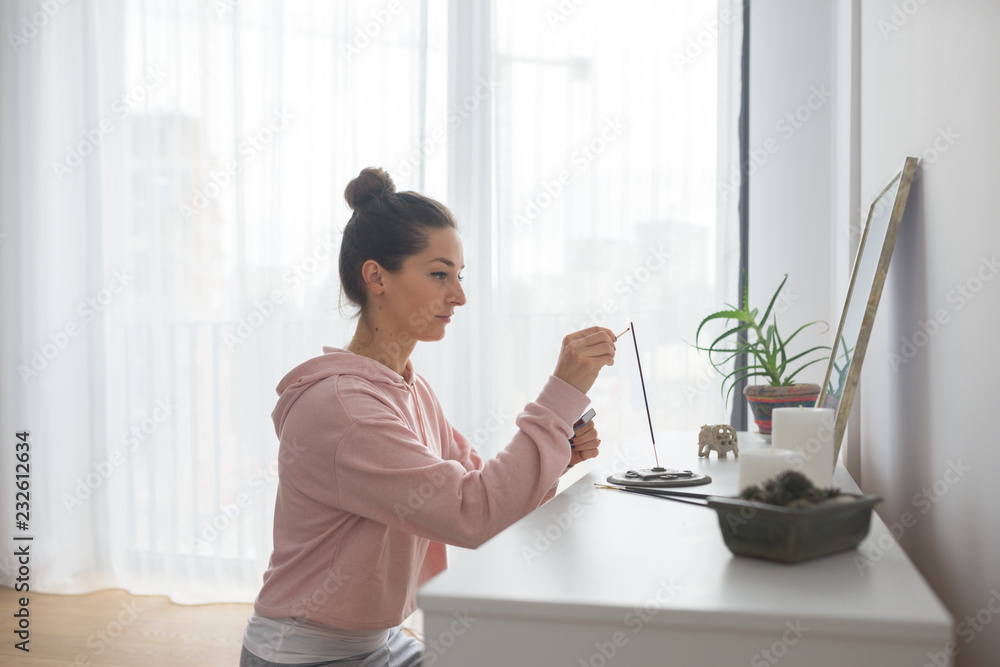Caucasian woman lighting up a scented stick in her room Caucasian woman lighting up a scented stick in her room