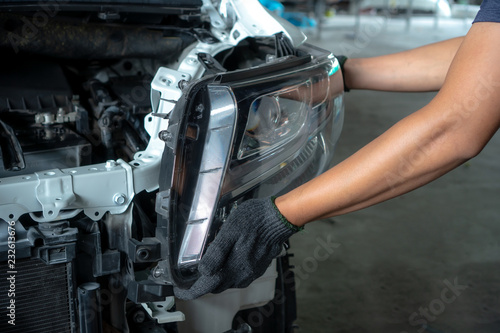 Mechanic changing car headlight in a workshop
