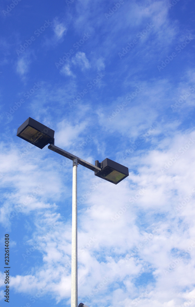 Overhead lights against blue sky with clouds Overhead lights against blue sky with clouds