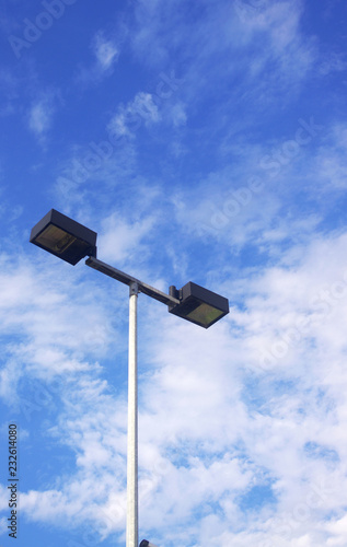 Overhead lights against blue sky with clouds