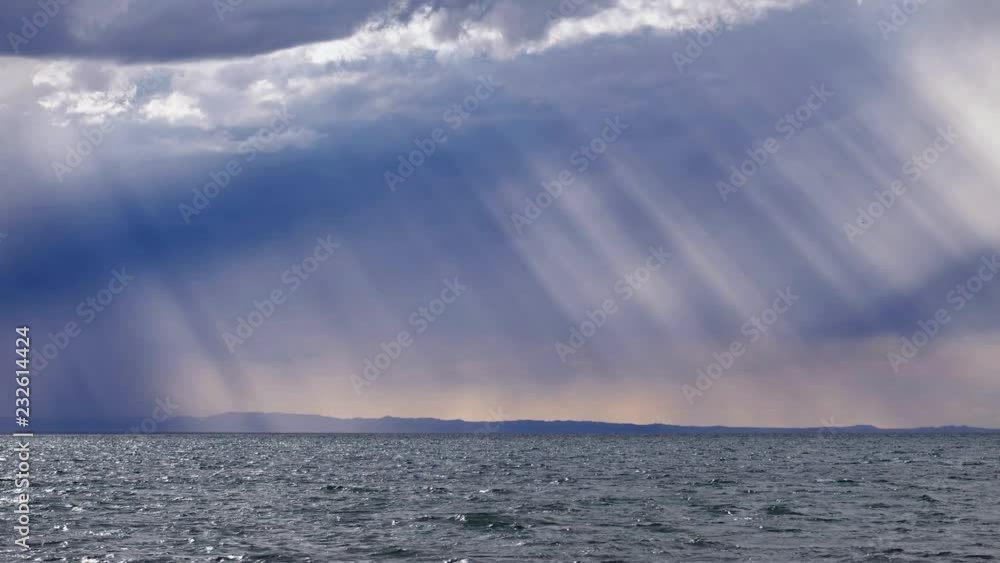 Rain and the sun's rays through the dramatic clouds in the sky over mongolian lake Durgen Nuur in Mongolia. Rain and the sun's rays through the dramatic clouds in the sky over mongolian lake Durgen Nuur in Mongolia.