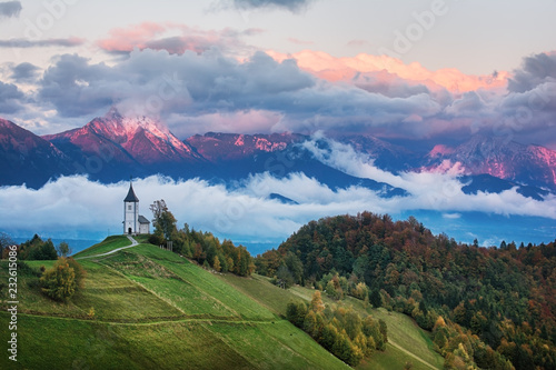 Beautiful sunrise landscape of church Jamnik in Slovenia with cloudy sky photo