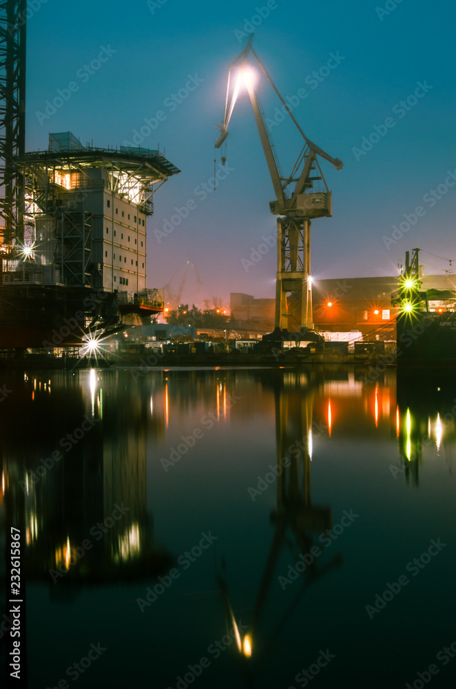 Fototapeta premium Dźwig portowy, odbicie w wodzie, wschód słońca. 