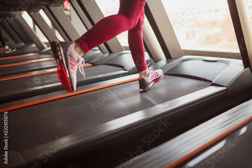 Crop sportswoman running on treadmill