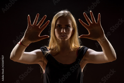 Young woman waving her hands. Blonde girl expressing with raised hands their emotions in a studio on a black background