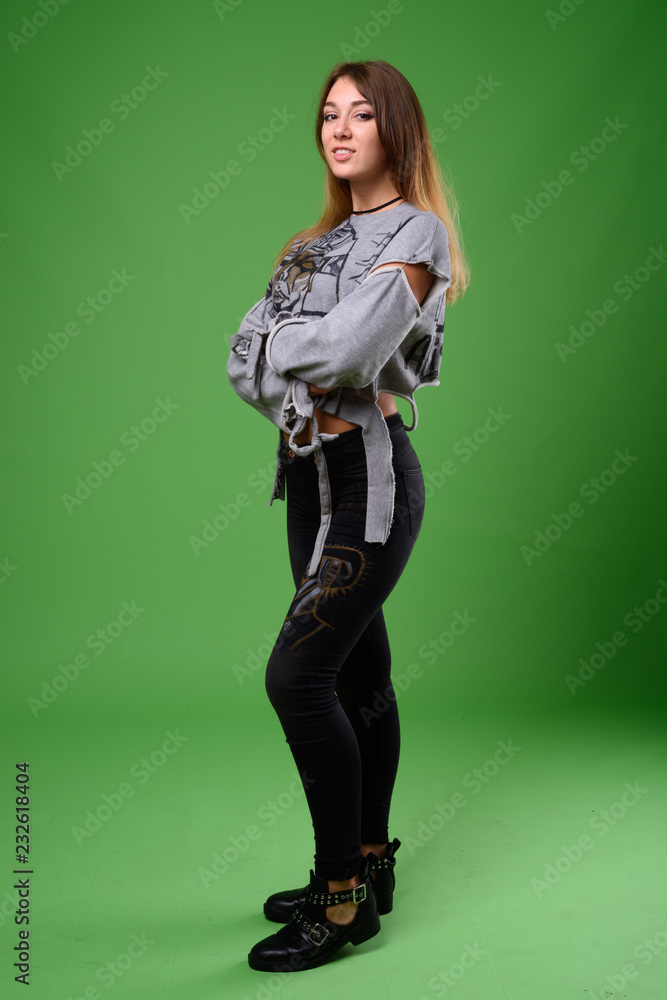 Young beautiful rebellious woman against green background