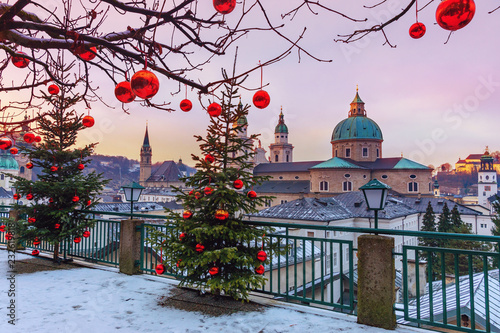 Beautiful view of the historic city of Salzburg with famous Salzburg Cathedral in winter, Austria.Christmas trees with red Christmas balls against the background of the winter Salzburg.