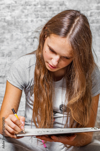 Tableau sur toile portrait of young teenager brunette girl with long hair drawing with pencil on g