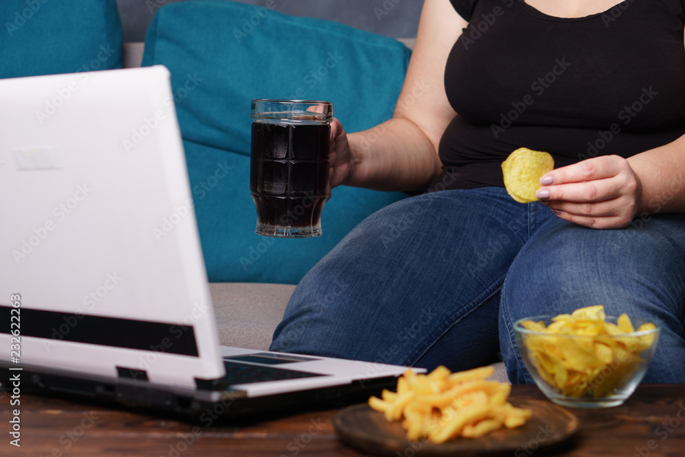 lack of physical activity, remote work, laziness, homebody. Lonely woman watching series at laptop drink beer eat junk food lack of physical activity, remote work, laziness, homebody. Lonely woman watching series at laptop drink beer eat junk food