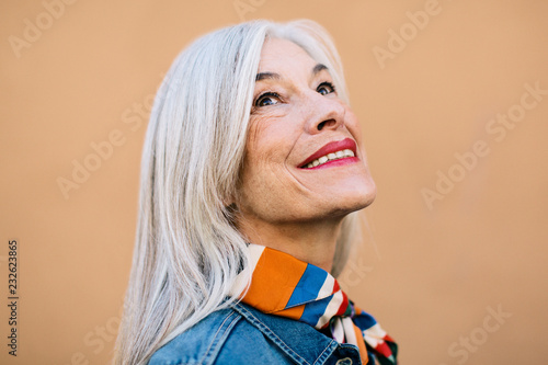 Portrait of a cool senior woman with grey long hair smiling.
