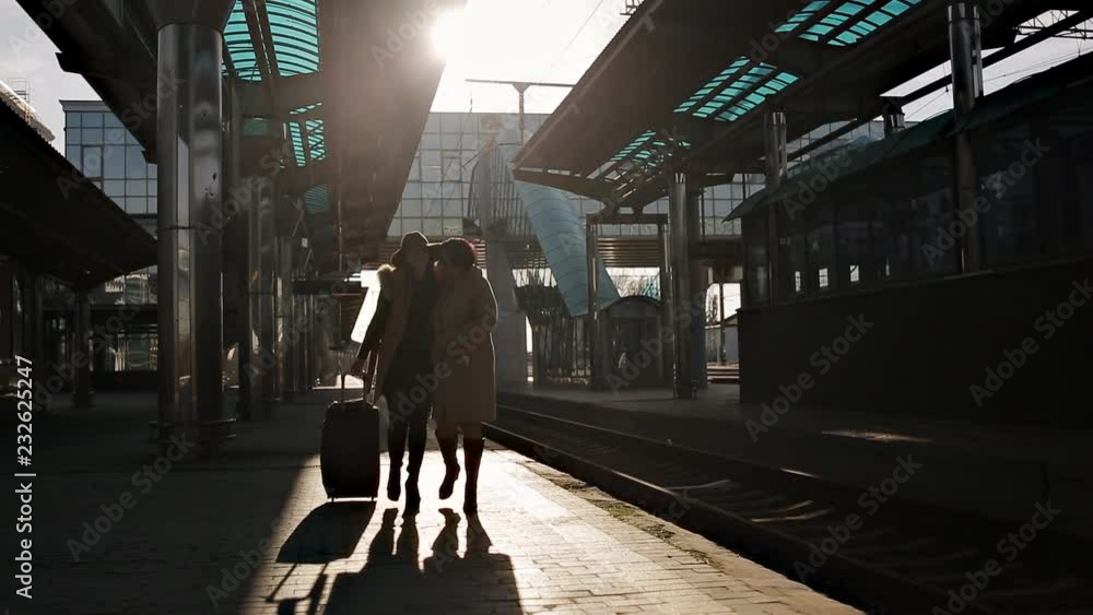 Women silhouettes in the sunset light of the sun, at the railway station go to the train. Women silhouettes in the sunset light of the sun, at the railway station go to the train.