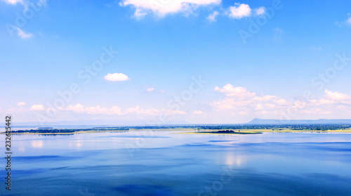 Beautiful blue sky with clouds and lake. There are lands in the lake.