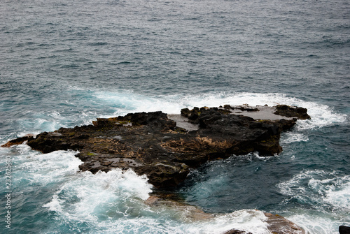 A dark rock in the waves of the ocean