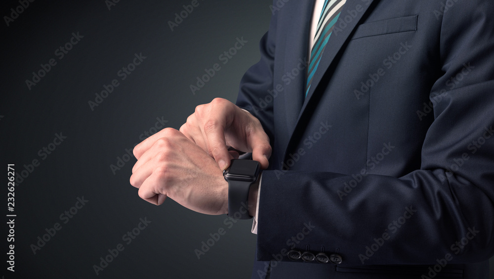 Obraz premium Man wearing suit with smartwatch on his wrist.