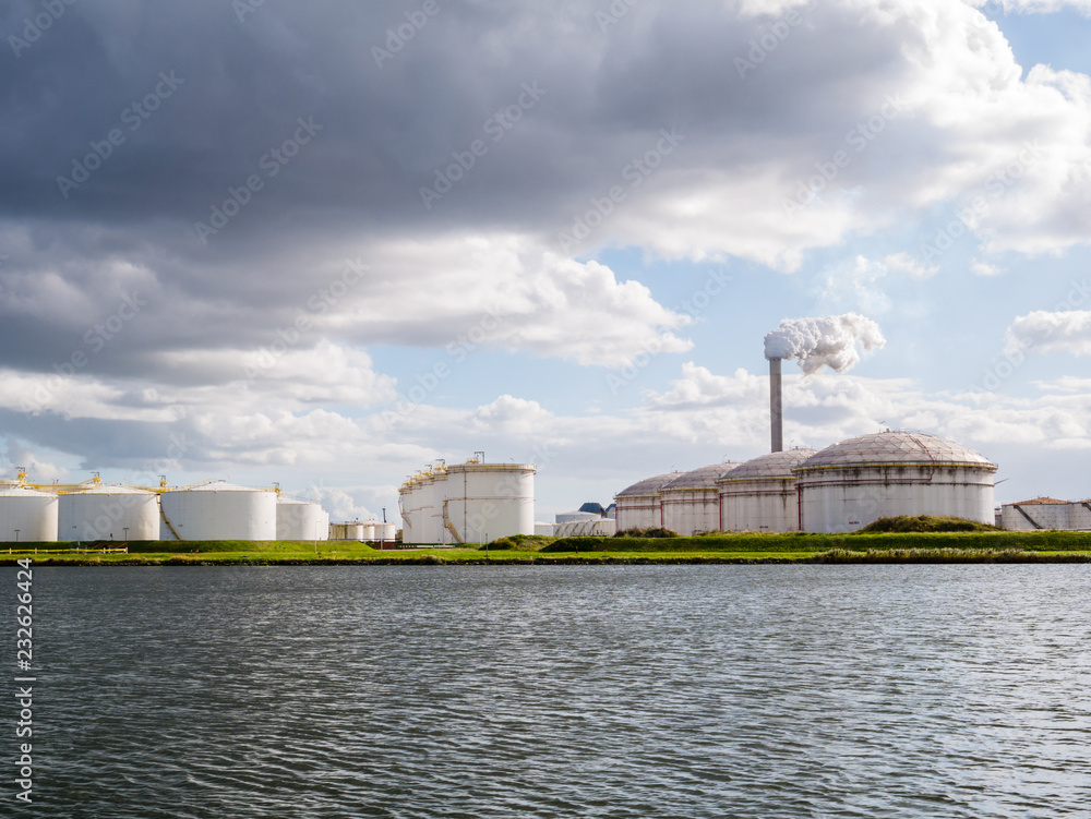 Obraz premium Oil storage tanks and exhaust stack of power station Hemweg in Westpoort, Port of Amsterdam, Netherlands