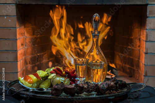 Traditional homemade Russion  herbal infused vodka with cold snacks and firplace on background photo