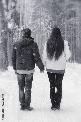 A loving couple on a winter walk. Man and woman on a date in the park in winter. Friends in a winter park © alexkich