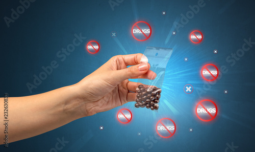 Hand giving pills with anti-drug concept and not allowed signs around photo