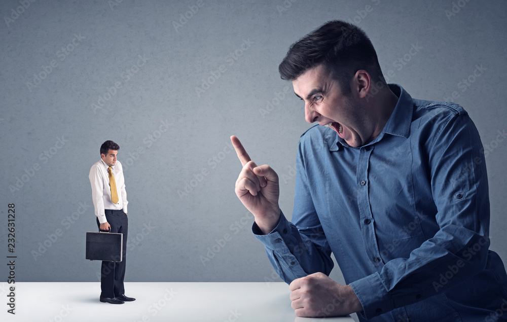 Young professional businessman being angry with an other miniature businessman Young professional businessman being angry with an other miniature businessman