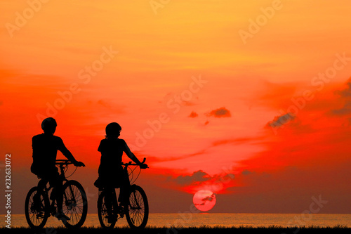 silhouette couple ride bike on sunrise