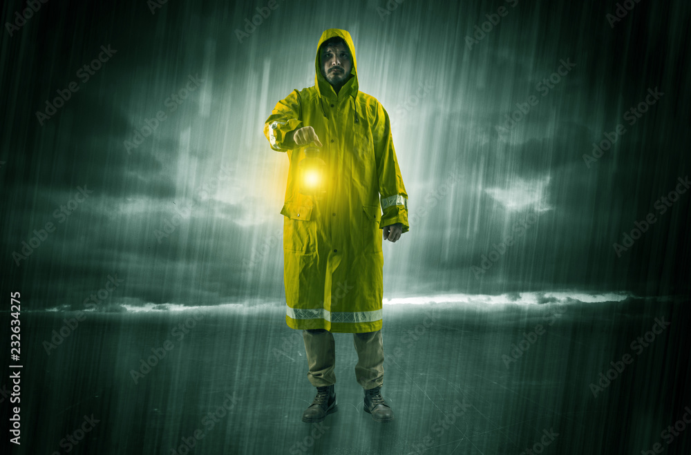 Fototapeta premium Raincoated man walking in storm with glowing lantern in his hand 