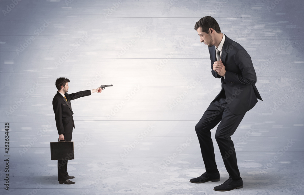 Tiny businessman with gun shooting giant fearful businessman
Tiny businessman with gun shooting giant fearful businessman
