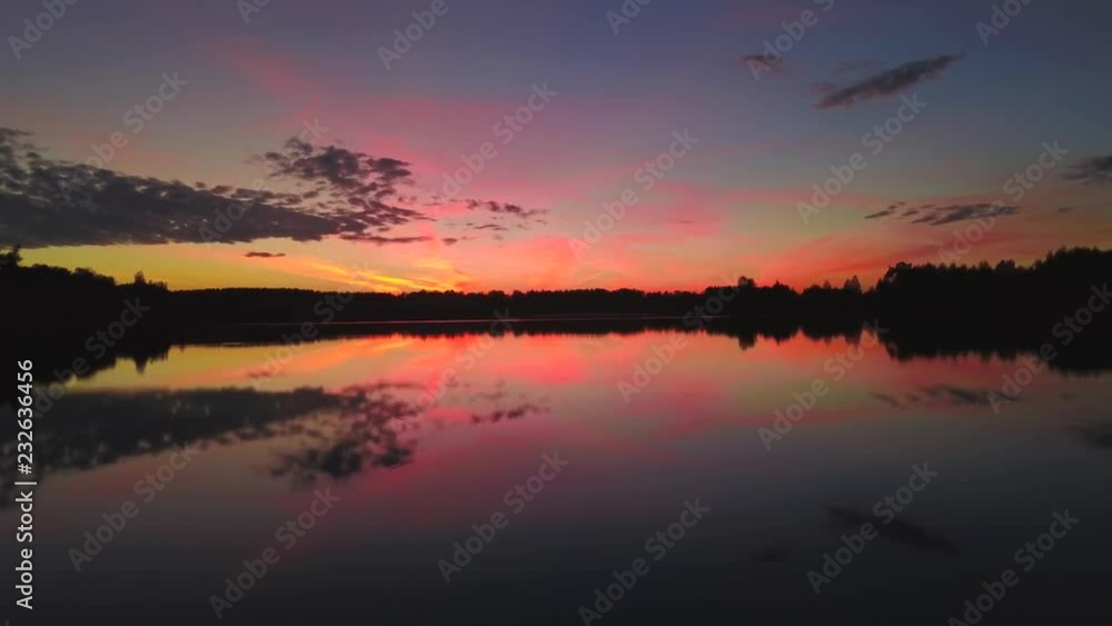 Flying over lake with reflection of sky and pink sunset Flying over lake with reflection of sky and pink sunset